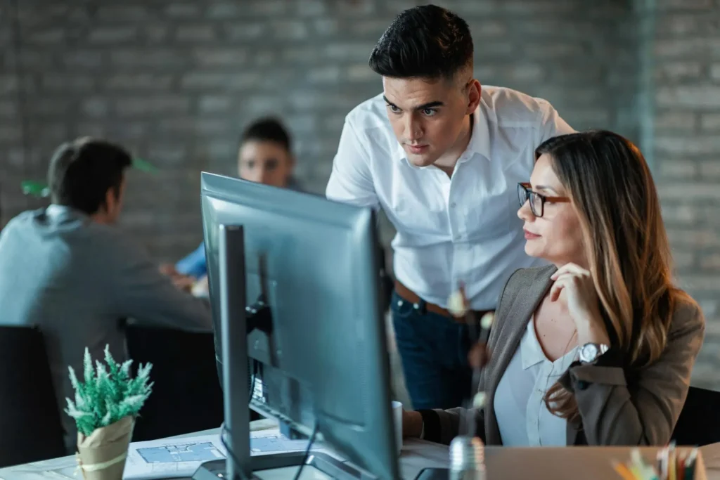 two young business colleagues using desktop pc reading email while working together office focus is man