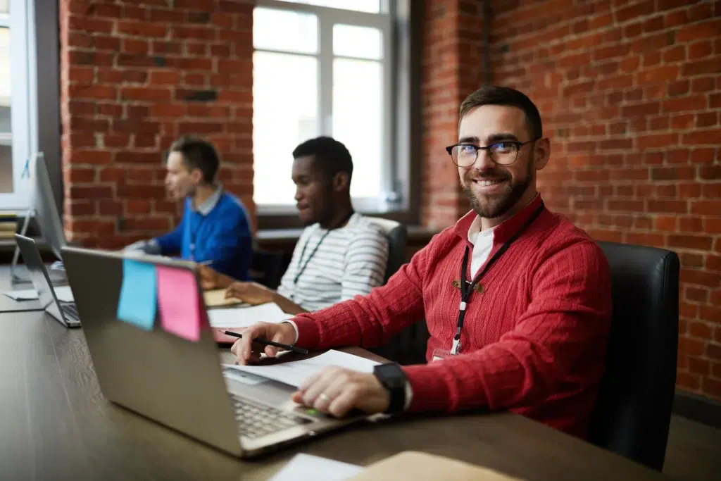 Hire Remote Developers in 2026: Why the Nearshore Model is Outperforming Offshore Teams 1 Confident developer in a red sweater, part of a team you can hire remote developers.