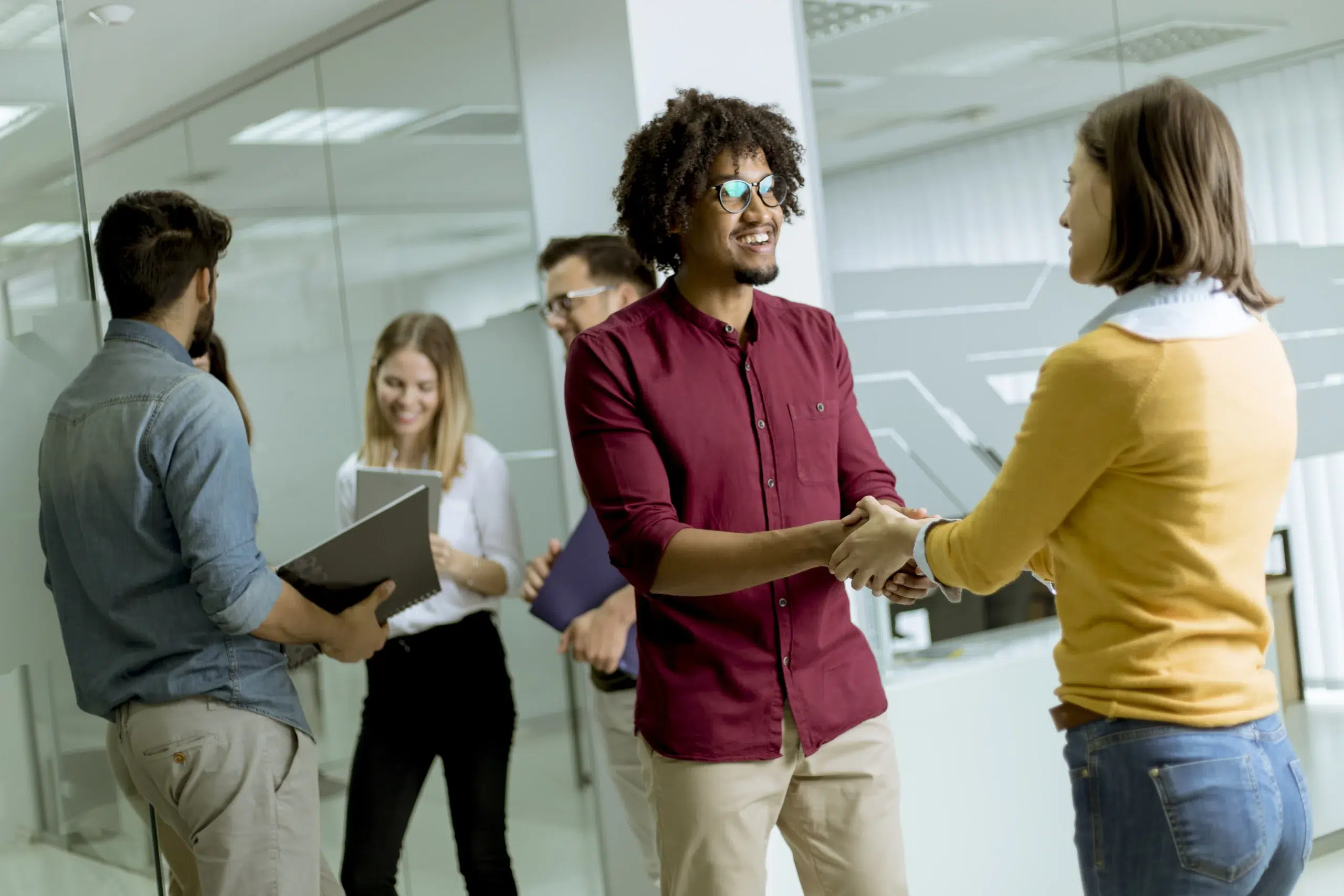 Creative professionals shaking hands in an office setting for it staff augmentation.