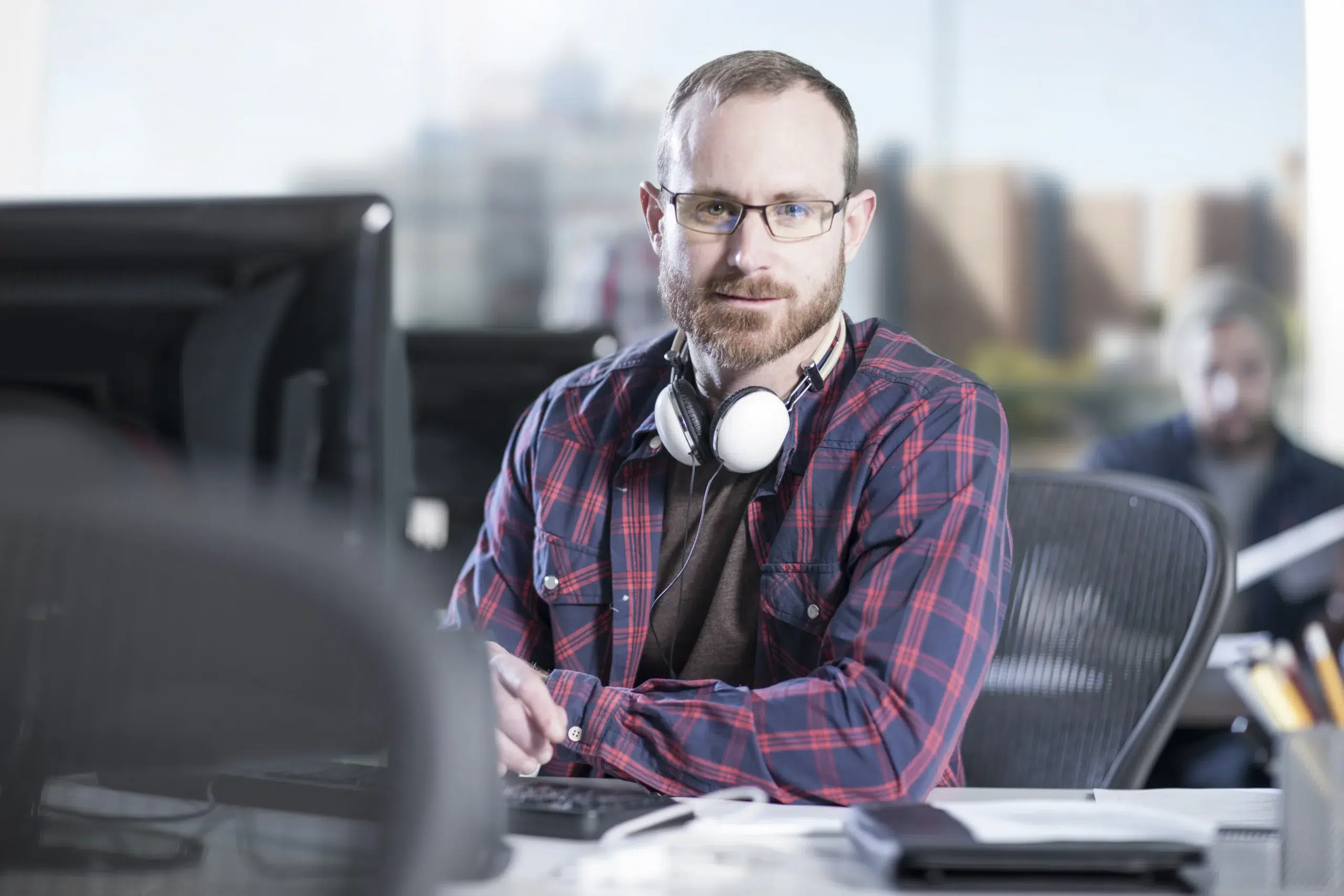 Professional with a plaid shirt at a computer workstation, representing the expertise you get when you hire remote developers.