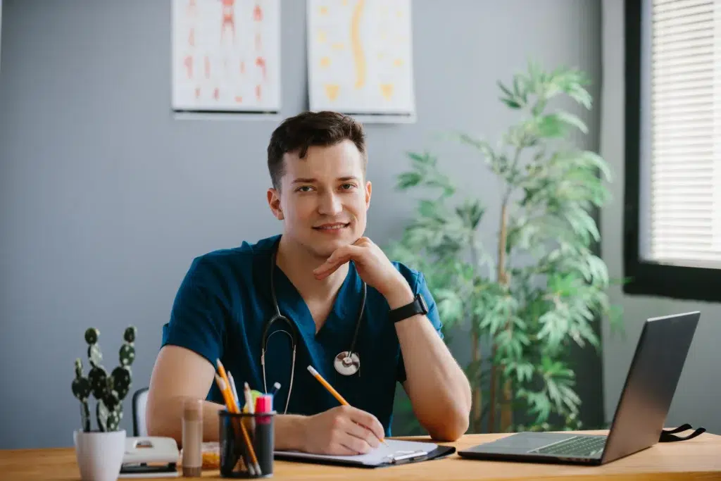 Modifier 25 Rules: Why Most Practices Get This Medical Billing Tool Wrong 1 Young doctor at a desk writing a note to support modifier 25.