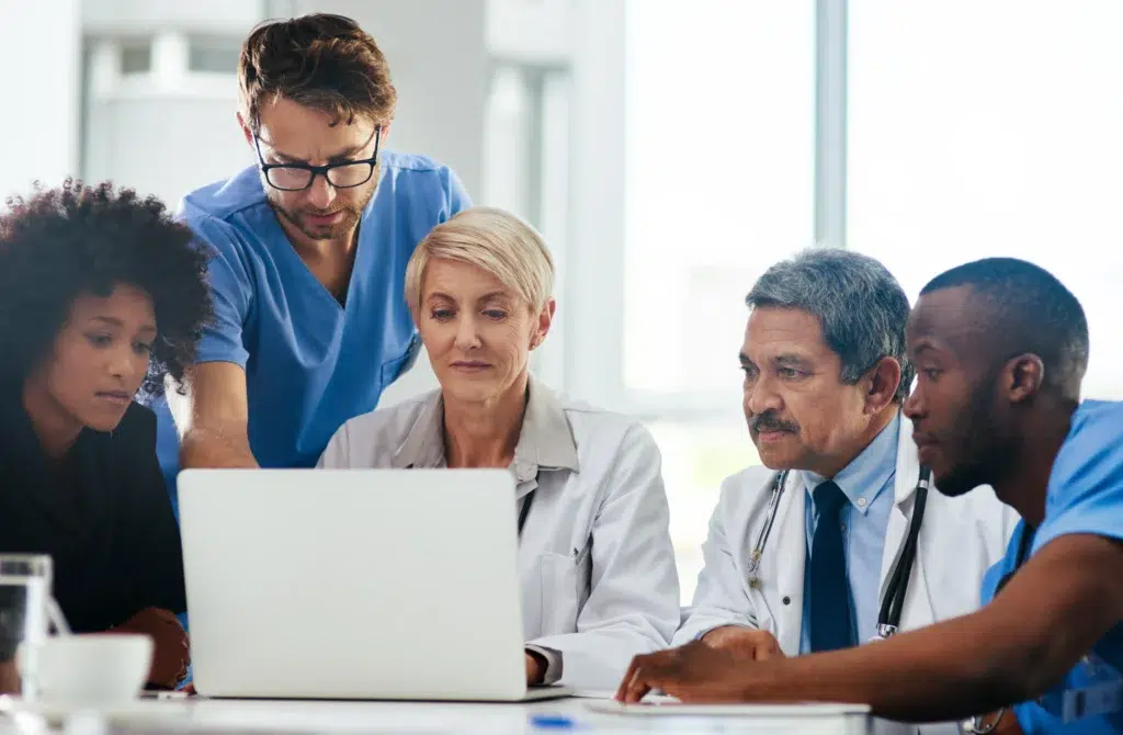 Modern Medical Billing: What is Revenue Cycle Management in 2026 and the Shift Toward Specialized Outsourcing 1 A diverse team of doctors and medical staff discussing what is revenue cycle management on a laptop.