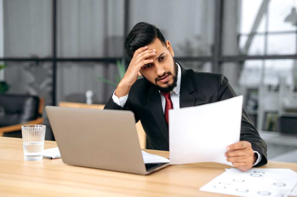 Concerned healthcare executive reviewing denial management in medical billing reports at his desk