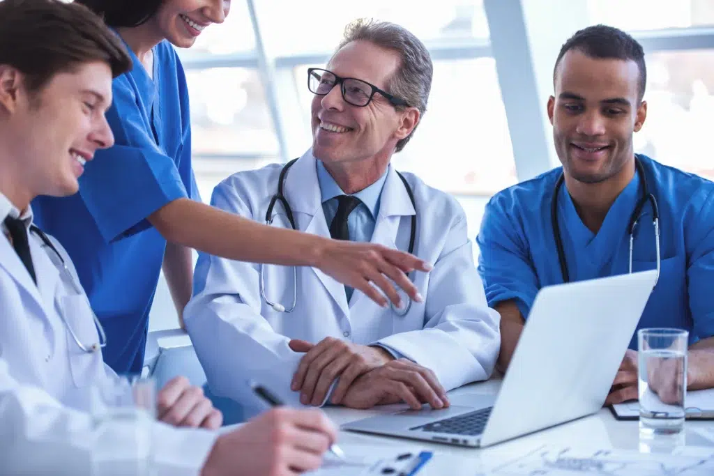 Medical Coding Outsourcing Services: Why Specialty Expertise Is the Only Thing That Actually Matters 1 Smiling medical coding outsourcing services team reviewing specialty billing data together