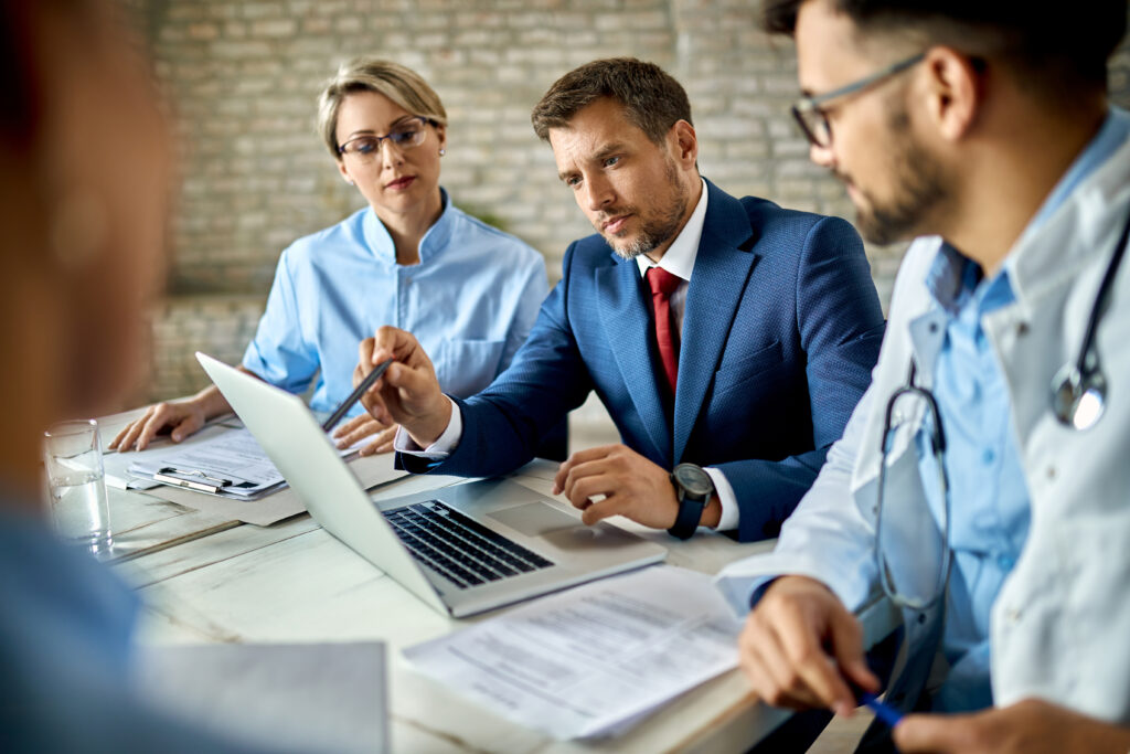 Outsourced Billing Services: What Healthcare Decision-Makers Need to Know Before Choosing a Partner 3 Healthcare decision-makers and business consultant discussing outsourced billing services on laptop