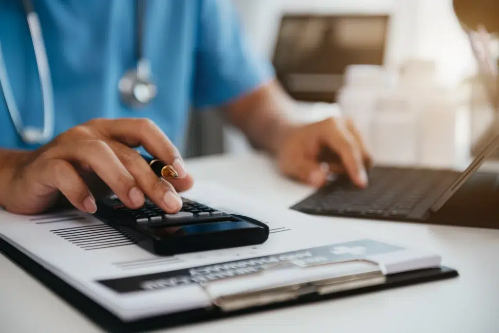How to Outsource Medical Billing Services Without Disrupting Your Practice 1 Healthcare administrator calculating medical billing costs before deciding to outsource medical billing services