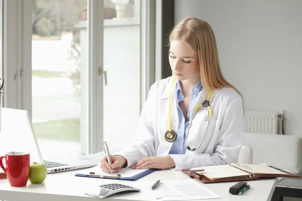 Physician documenting prior authorization requests at her desk