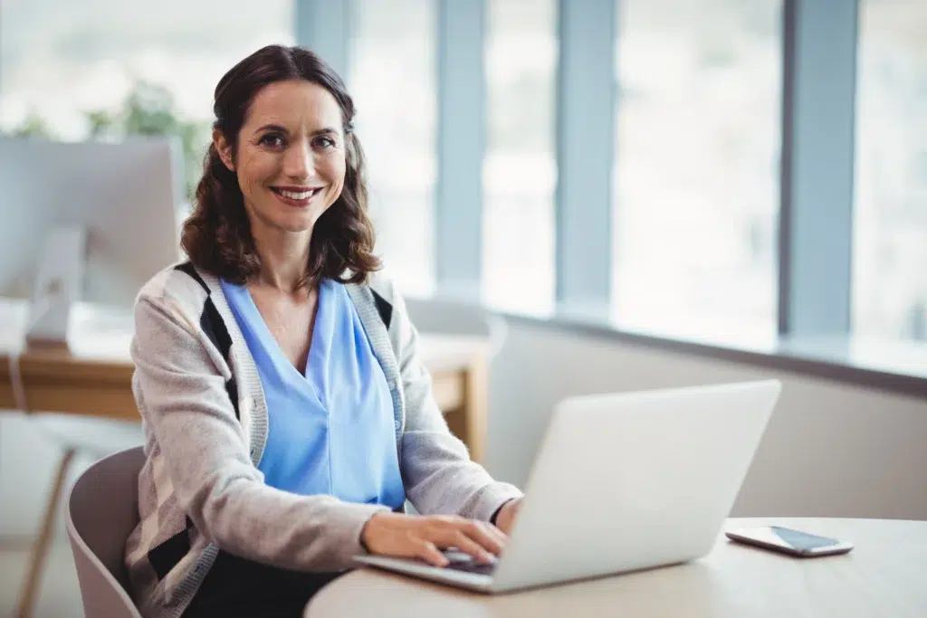 Smiling medical executive reviewing 99211 CPT code billing requirements at her desk in a healthcare practice