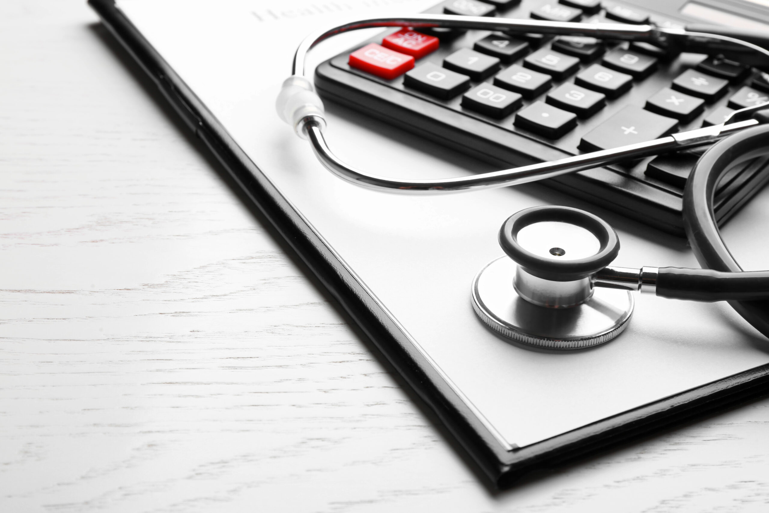 Calculator and stethoscope representing the intersection of clinical care and EOB medical billing reconciliation in healthcare revenue cycle management