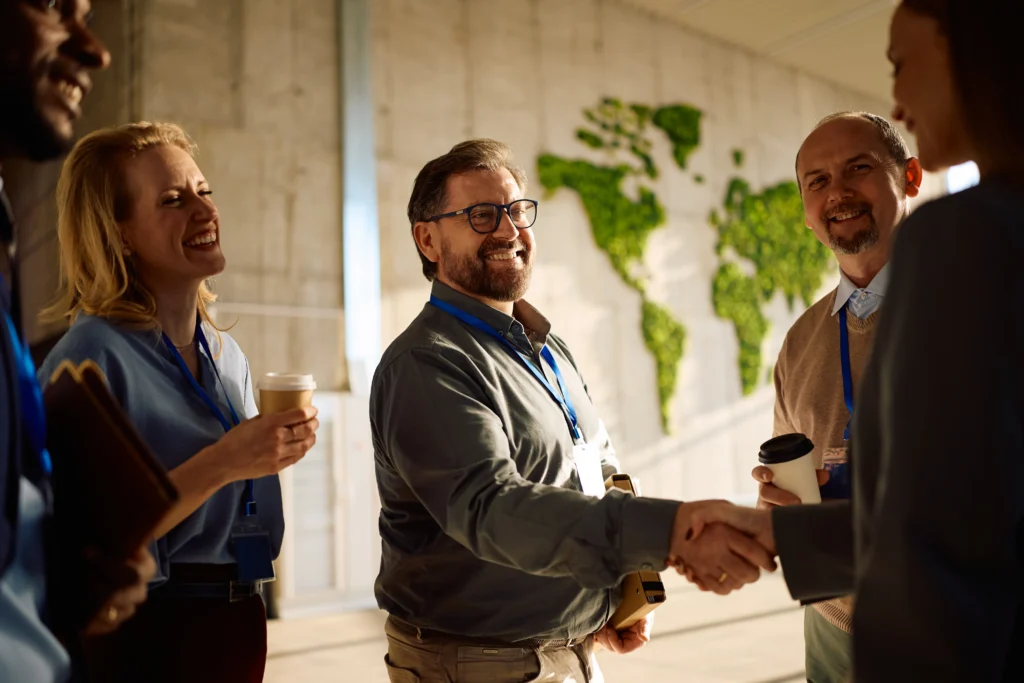 Professionals shaking hands and networking at a corporate event, reflecting the shift toward nearshore outsourcing across industries