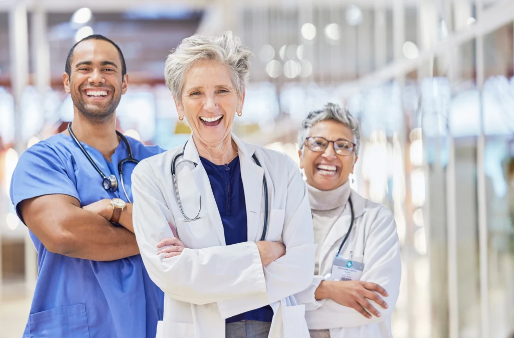 Why Health Systems Are Consolidating RCM Vendors Under One Healthcare Partner in 2026 1 Confident healthcare team with arms crossed in a hospital hallway, representing the stability healthcare vendor management companies provide when RCM functions are consolidated