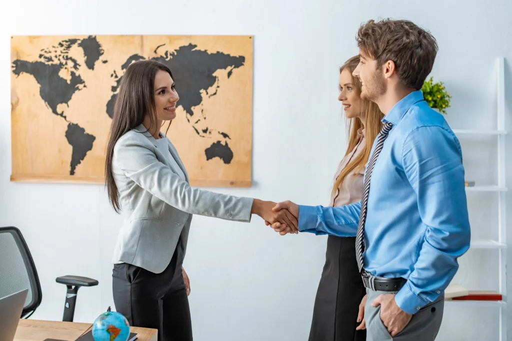 Colleagues shaking hands in an office with a world map, representing a new nearshore outsourcing partnership in Latin America