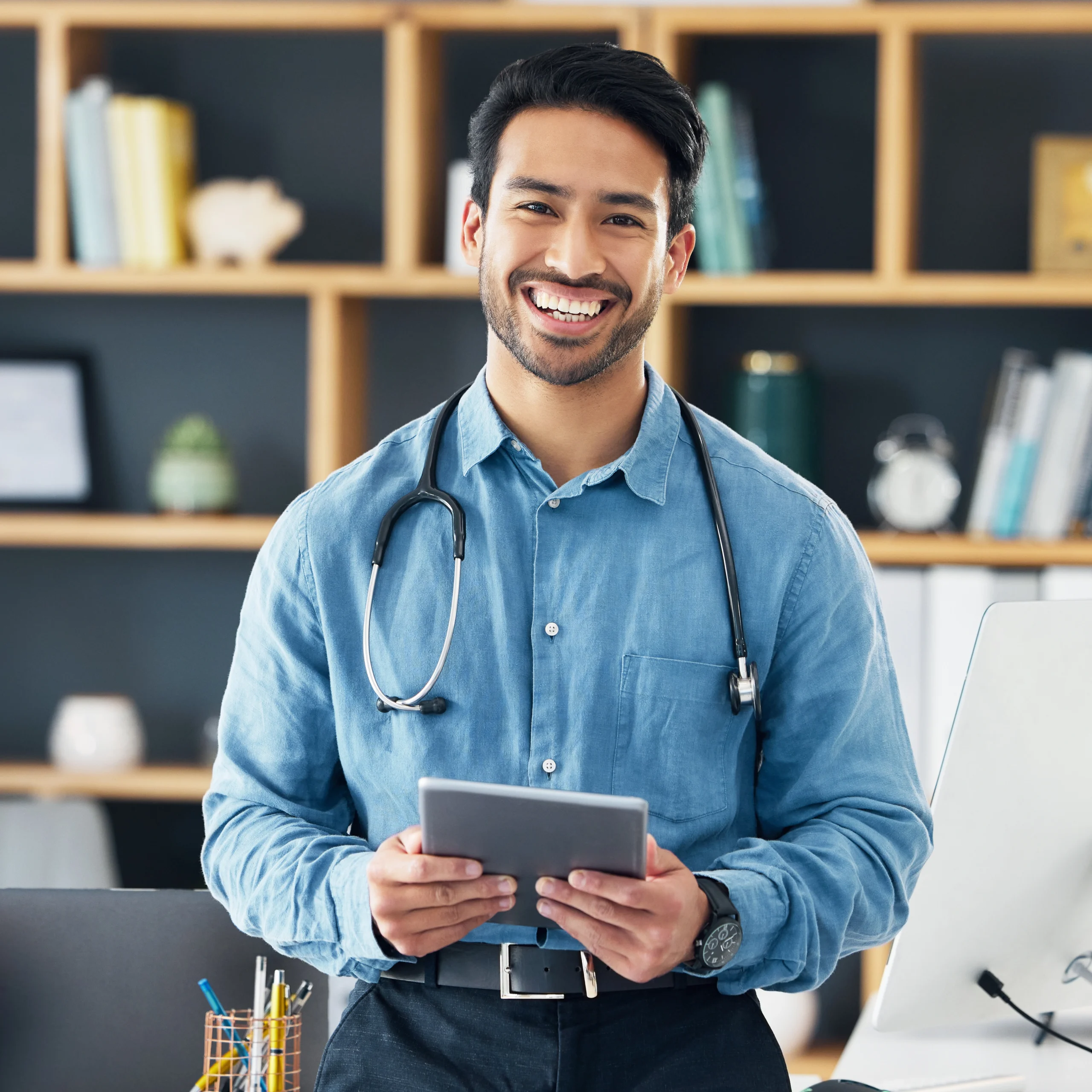 Smiling physician holding a tablet after completing medical credentialing services