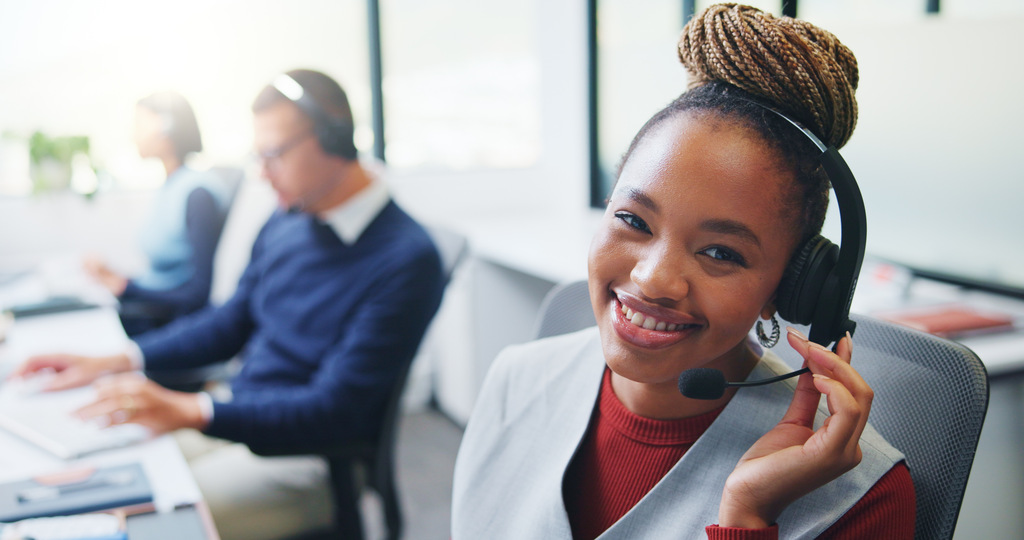 Smiling customer service outsourcing representative wearing a headset in a support center